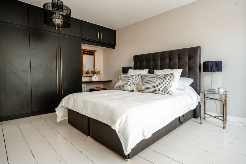 Twin adjustable bed with black upholstery in modern bedroom with a bed, nightstands, and wardrobe.
