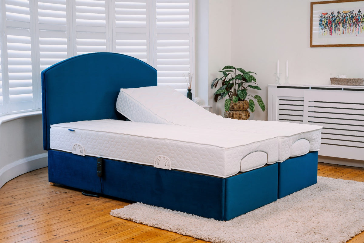 Blue Adjustable bed frame with white mattress in a room with wooden floor and white walls.